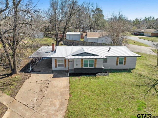 view of front of house with a front lawn, driveway, metal roof, an attached carport, and a chimney