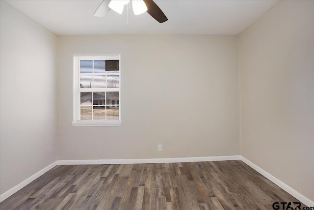 empty room with baseboards, dark wood finished floors, and a ceiling fan
