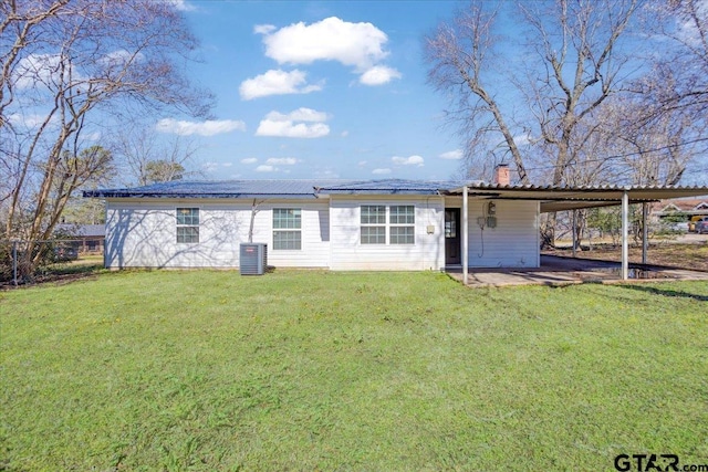 view of front of home with a carport, cooling unit, a front yard, and a chimney