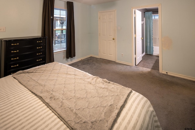 bedroom with dark colored carpet, connected bathroom, and baseboards