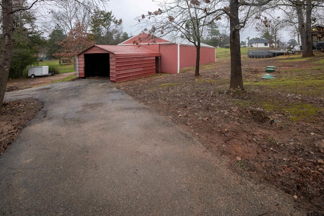 exterior space with driveway, a pole building, and an outbuilding