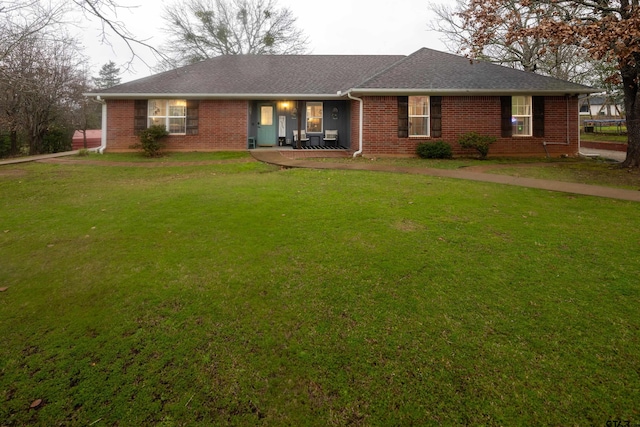 ranch-style house featuring roof with shingles, a front lawn, and brick siding