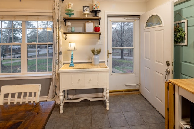 doorway to outside featuring baseboards, a wealth of natural light, and dark tile patterned flooring