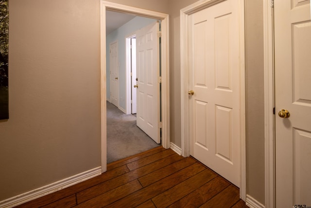 corridor featuring dark wood-style flooring and baseboards