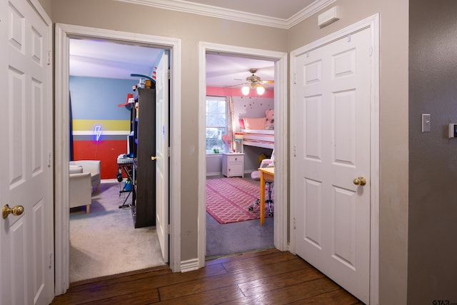 hall featuring dark wood-style floors, baseboards, and crown molding