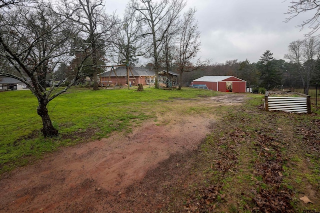 view of yard with an outbuilding, a detached garage, an outdoor structure, driveway, and a vegetable garden