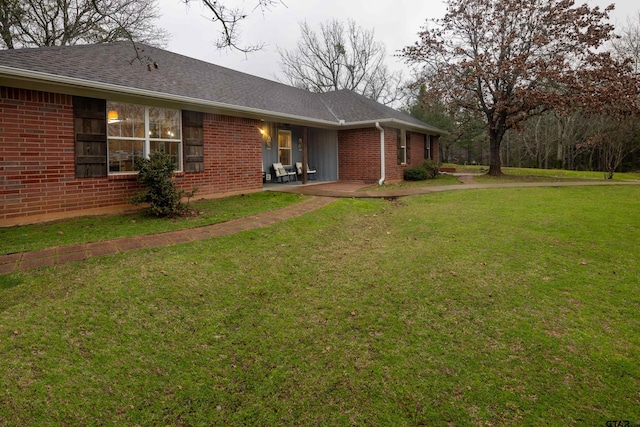 exterior space featuring a yard, brick siding, and roof with shingles