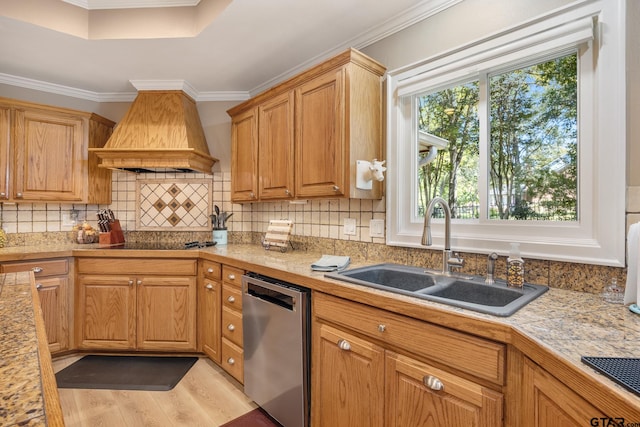 kitchen with premium range hood, ornamental molding, light wood-type flooring, sink, and dishwasher