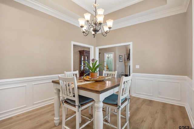 dining area featuring ornamental molding, light hardwood / wood-style flooring, and an inviting chandelier