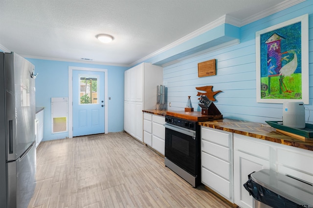 408 Morton Ave, Palacios, TX 77465 - kitchen featuring freestanding refrigerator, butcher block counters, ornamental molding, white cabinets, and a textured ceiling