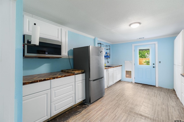 408 Morton Ave, Palacios, TX 77465 - kitchen featuring appliances with stainless steel finishes, crown molding, white cabinetry, a textured ceiling, and a sink
