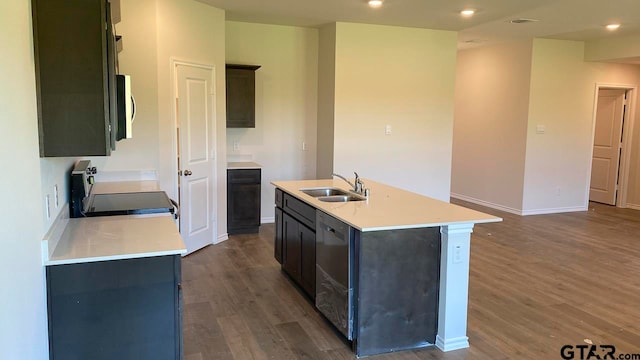 kitchen with an island with sink, sink, dark wood-type flooring, and appliances with stainless steel finishes