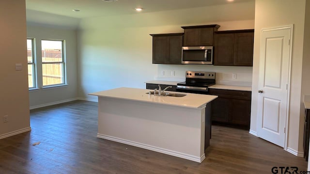 kitchen with dark hardwood / wood-style floors, a center island with sink, sink, and appliances with stainless steel finishes