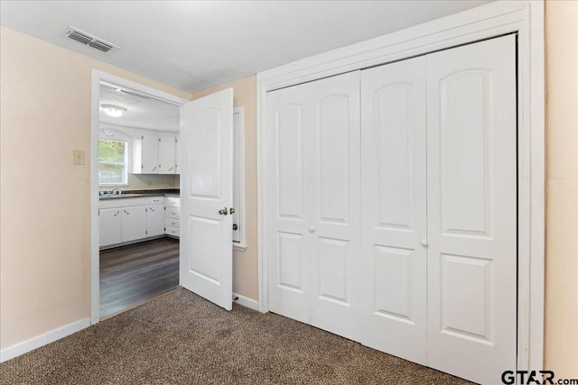 unfurnished bedroom featuring dark carpet, a textured ceiling, and a closet