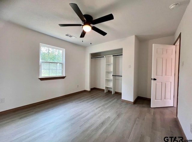 unfurnished bedroom featuring ceiling fan, a closet, wood-type flooring, and a textured ceiling