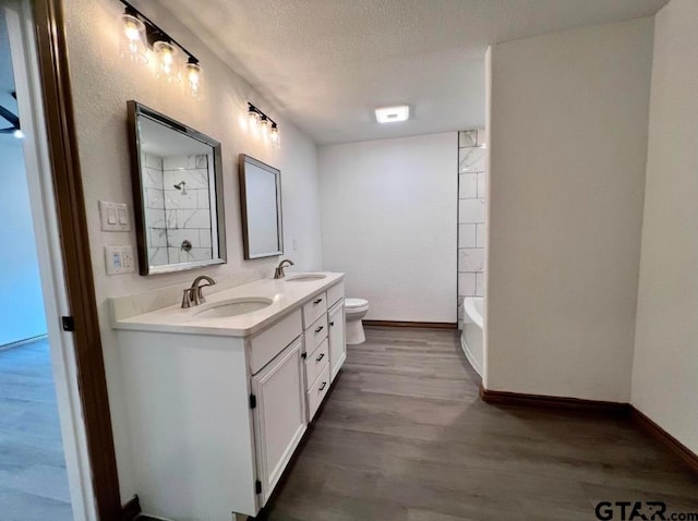 full bathroom with hardwood / wood-style floors, vanity, toilet, a textured ceiling, and shower / bath combination