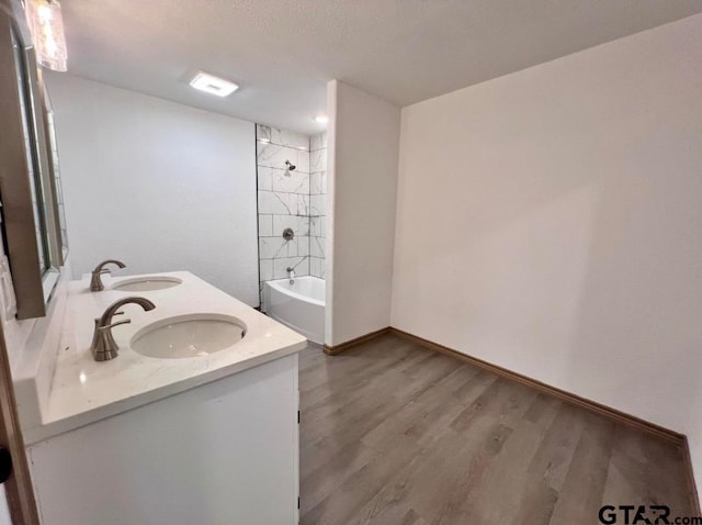 bathroom with hardwood / wood-style flooring, tiled shower / bath combo, and vanity