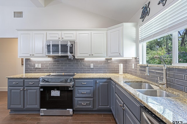 kitchen with tasteful backsplash, white cabinetry, appliances with stainless steel finishes, dark hardwood / wood-style floors, and vaulted ceiling