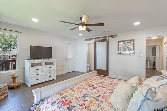 bedroom with ensuite bathroom, dark wood-type flooring, ceiling fan, and a barn door