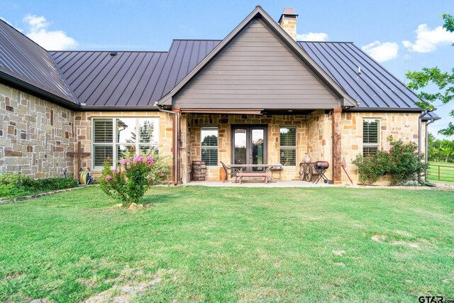 4180 N Smith Rd, Rockwall, TX 75087 - back of property featuring a standing seam roof, a metal roof, stone siding, a chimney, and a yard