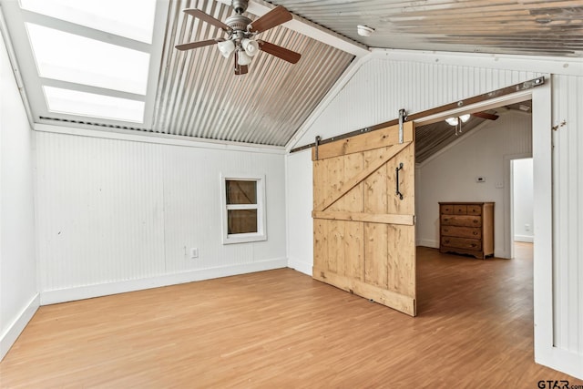 4180 N Smith Rd, Rockwall, TX 75087 - unfurnished living room featuring vaulted ceiling, a ceiling fan, wood finished floors, wooden walls, and a barn door