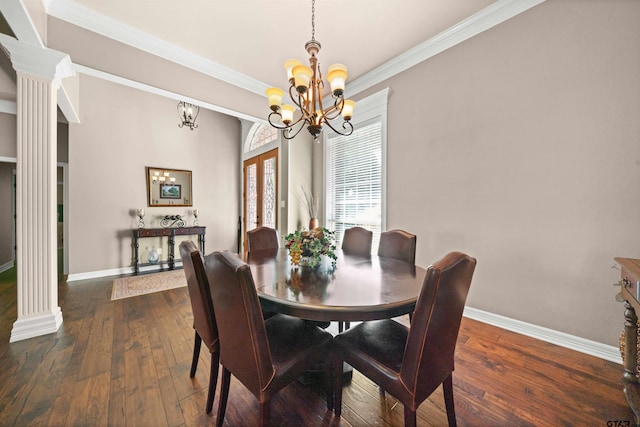 dining room with dark wood-type flooring, crown molding, decorative columns, and an inviting chandelier