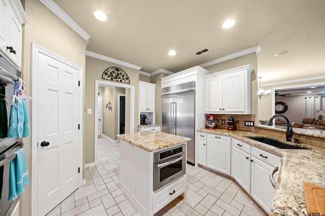 kitchen featuring stainless steel built in fridge, white cabinetry, pendant lighting, decorative backsplash, and sink