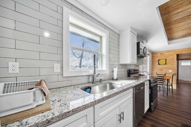 kitchen with dark wood-type flooring, sink, white cabinetry, stainless steel appliances, and light stone countertops