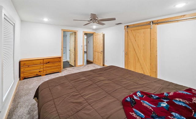 carpeted bedroom featuring ceiling fan and a barn door