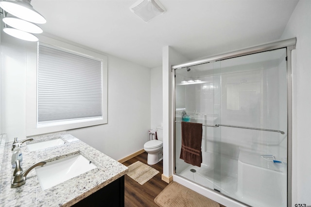 bathroom featuring vanity, a shower with shower door, hardwood / wood-style floors, and toilet