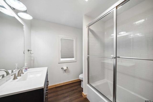 full bathroom with hardwood / wood-style flooring, vanity, shower / bath combination with glass door, and toilet