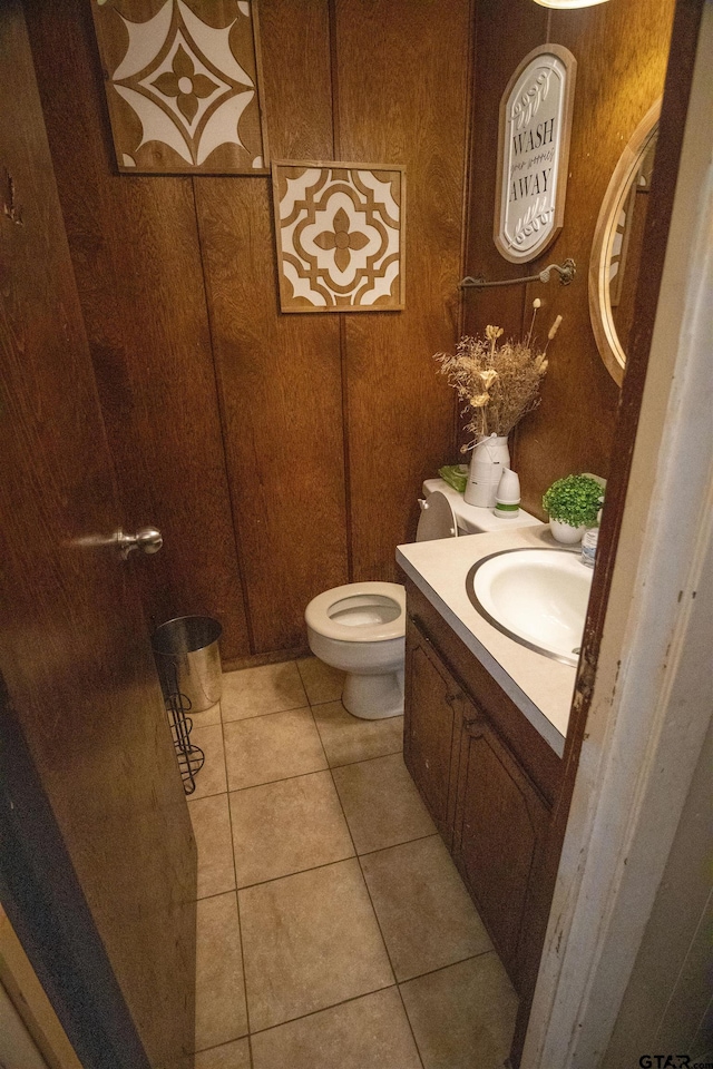 bathroom featuring vanity, toilet, wood walls, and tile patterned floors