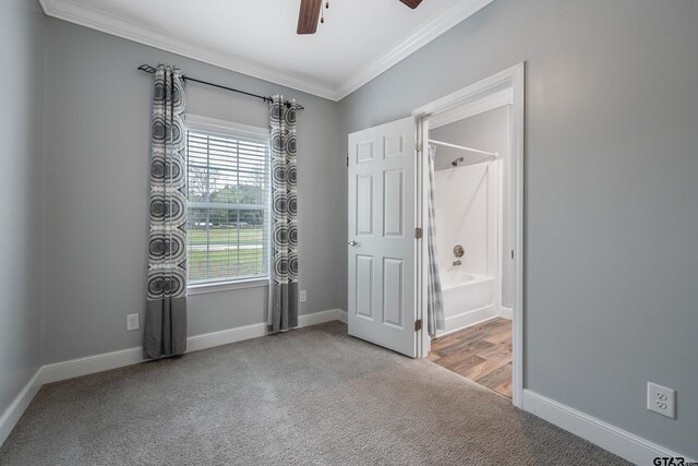 unfurnished bedroom with carpet flooring, a ceiling fan, crown molding, ensuite bathroom, and baseboards