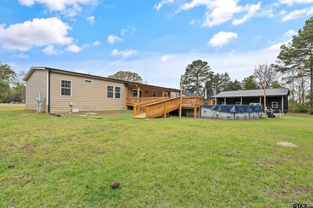 back of property with a covered pool, a deck, and a yard