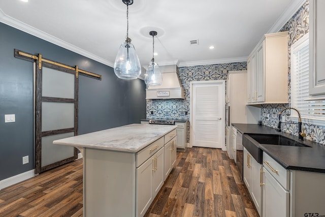 kitchen with a barn door, dark wood-style flooring, visible vents, a sink, and custom range hood