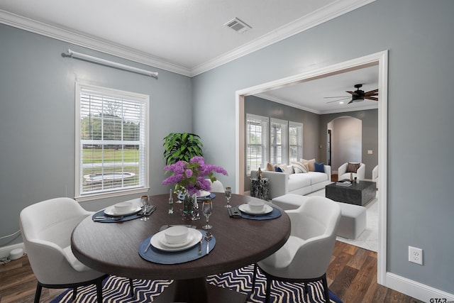 dining area with baseboards, visible vents, crown molding, wood finished floors, and arched walkways