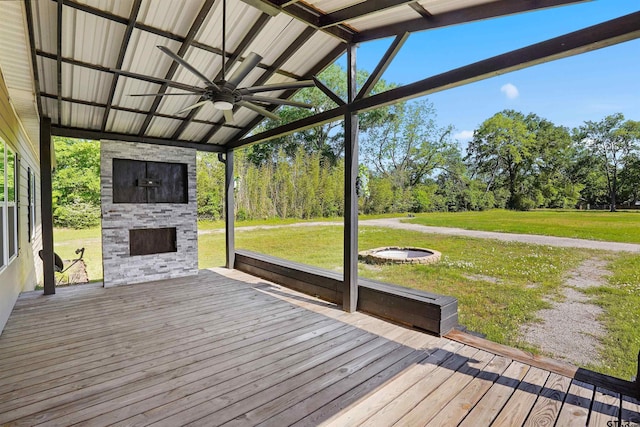 wooden terrace featuring a yard, an outdoor stone fireplace, and ceiling fan