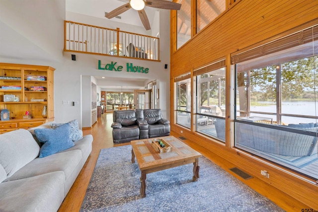 living room with plenty of natural light, ceiling fan, wood-type flooring, and high vaulted ceiling