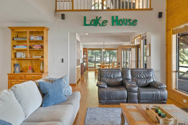 living room featuring wood walls, light hardwood / wood-style floors, and a towering ceiling