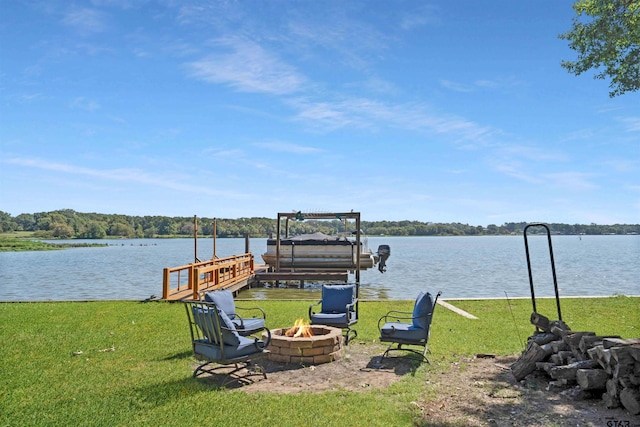 view of dock featuring a water view, a fire pit, and a lawn