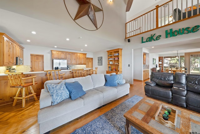 living room featuring light wood-type flooring and a high ceiling