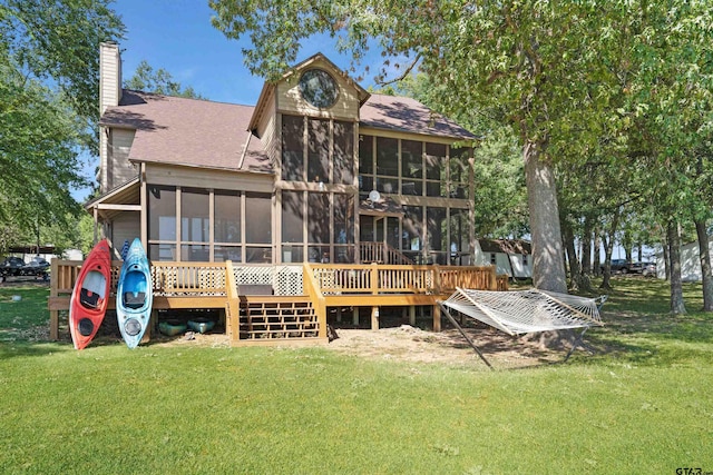 rear view of property with a lawn, a sunroom, and a deck