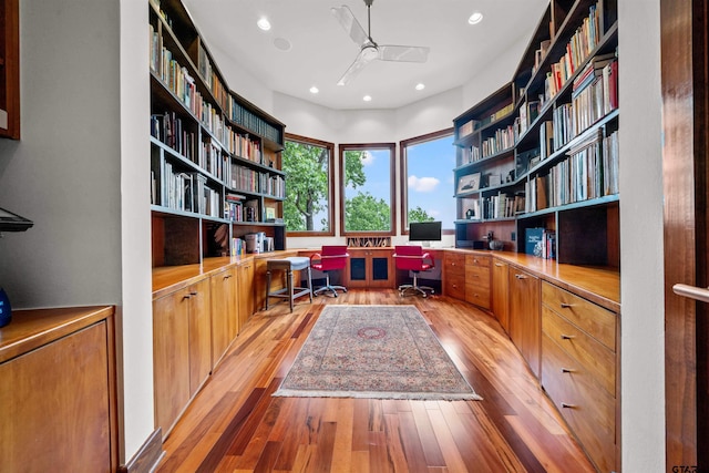 office featuring built in desk, light wood-type flooring, and ceiling fan