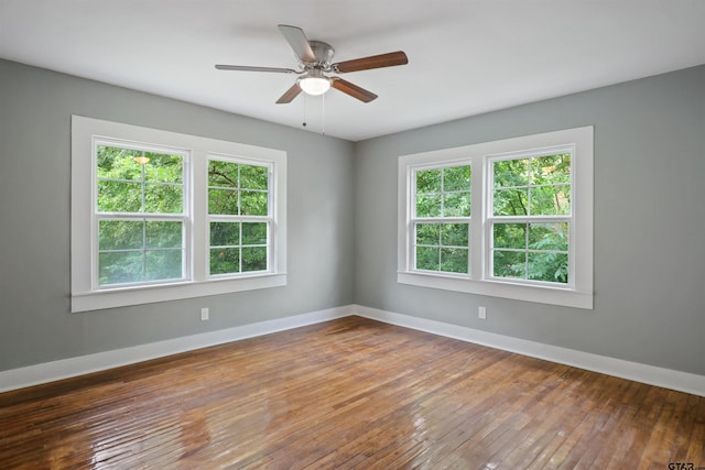 empty room with ceiling fan, plenty of natural light, and wood-type flooring