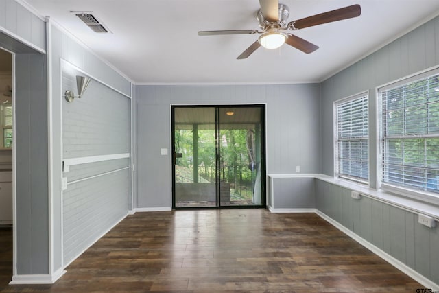 spare room with crown molding, a wealth of natural light, dark wood-type flooring, and ceiling fan