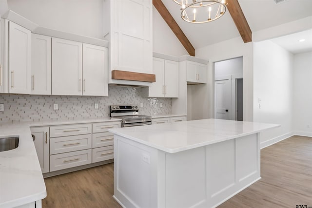 kitchen featuring tasteful backsplash, a kitchen island, electric range, decorative light fixtures, and white cabinetry