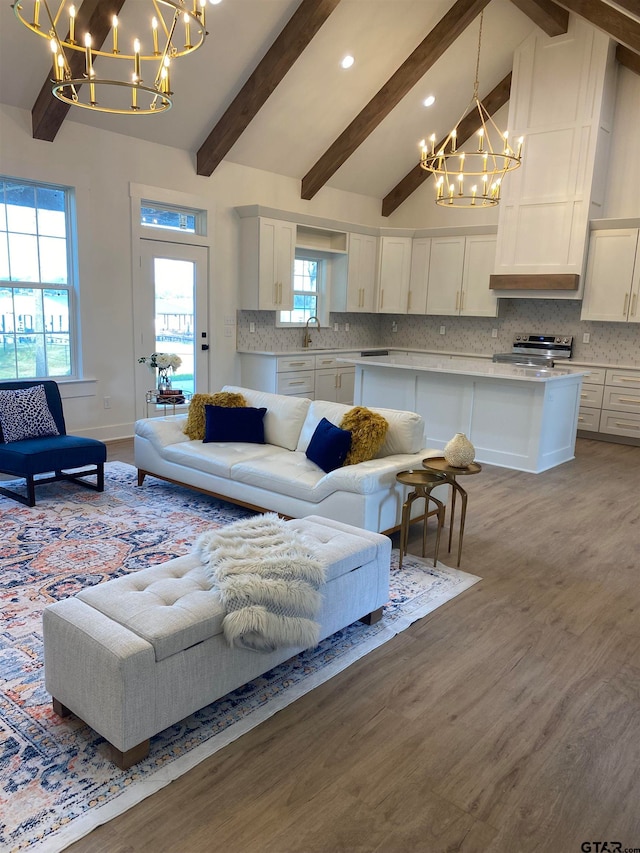 living room with hardwood / wood-style flooring, lofted ceiling with beams, sink, and an inviting chandelier