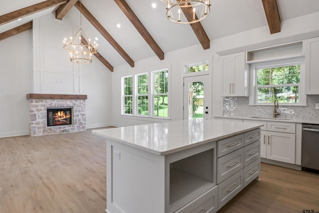 kitchen featuring beam ceiling, dishwasher, white cabinets, a kitchen island, and hanging light fixtures