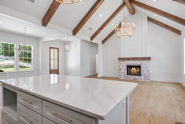 kitchen with gray cabinetry, a center island, decorative light fixtures, and light wood-type flooring