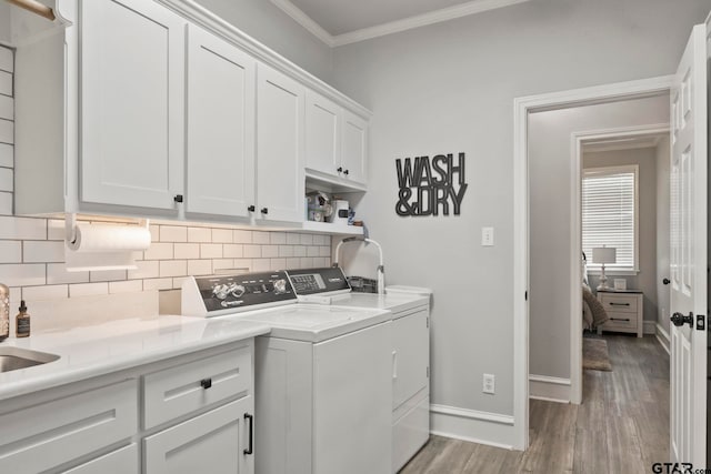 washroom featuring cabinets, sink, independent washer and dryer, light hardwood / wood-style flooring, and crown molding